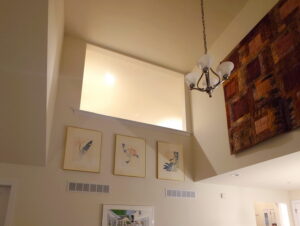 Hanging paintings and a tapestry high up, just below the ceiling.