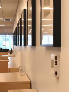 This photo showcases a stunning row of 10 perfectly aligned black frames mounted on a clean, white office wall